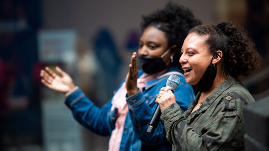 Two NIAD artists, Shawna clapping on the left and Esme with the microphone on the right, attend SFMOMA mini murals