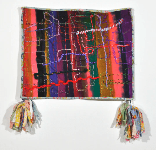 A square wallhanging shot through with zips of yarn and two tassels at both bottom corners.