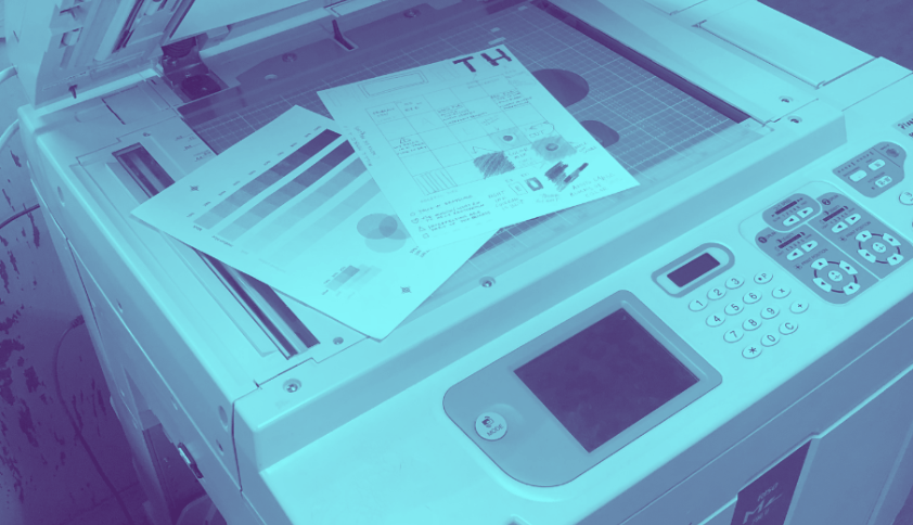 a blue-tinted photograph of riso prints on a risograph machine.