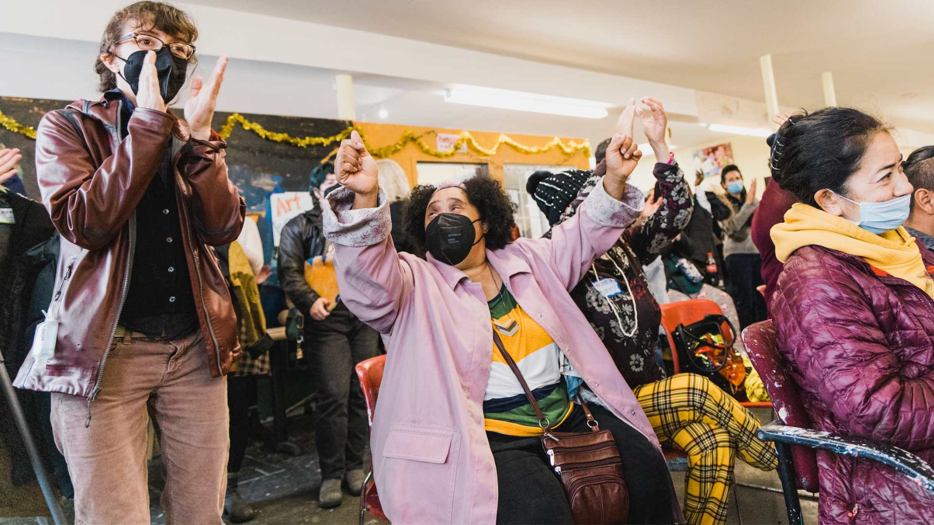 A NIAD volunteer and NIAD artist Halisi Noel-Johnson cheering in a crowd at a NIAD event.